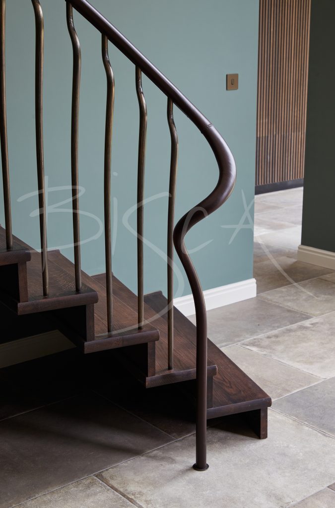Close-up of a leather-stitched handrail on a modern cantilever staircase, highlighting the dark brown leather and smooth curve.