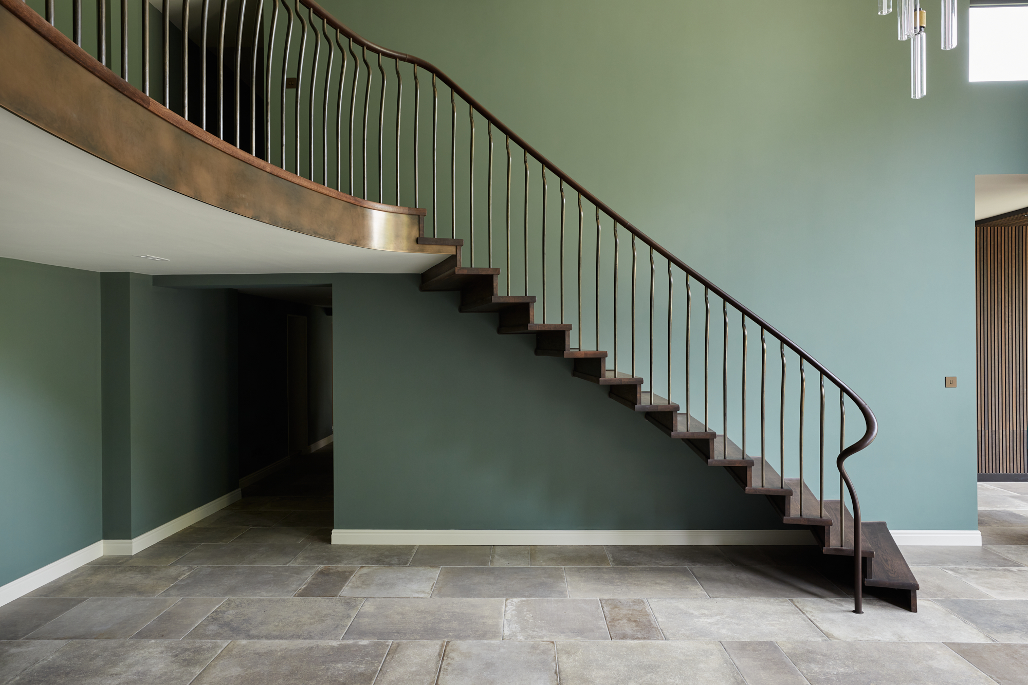 An elegant modern cantilever staircase with dark oak stained treads and hand forged balusters